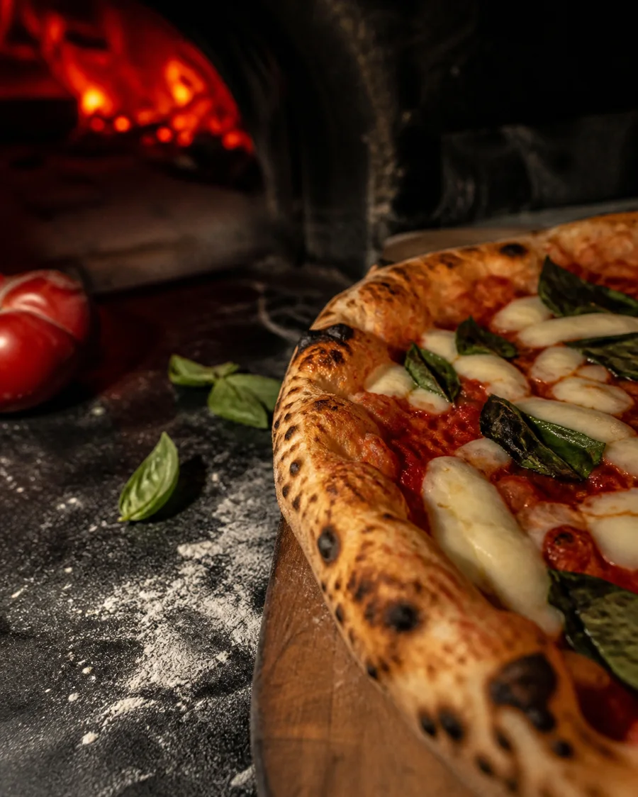Ingredientes e massa de pizza sobre bancada escura